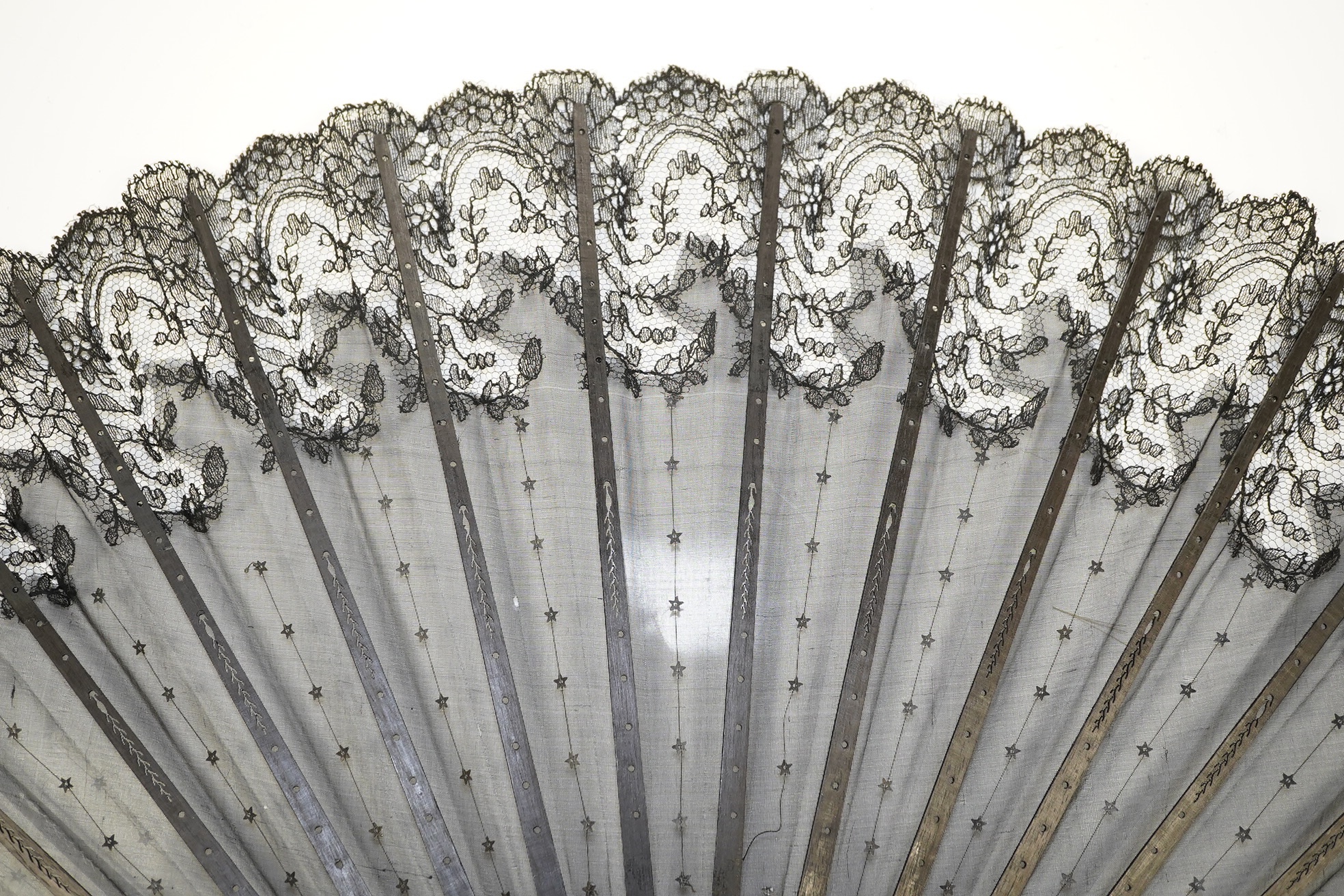 An Edwardian evening fan with black silk gauze, decorated sequin and lace trimmed leaf with carved ebonised guards and stems, in a fan box by J. D’uvelleroy. Condition - fair to good